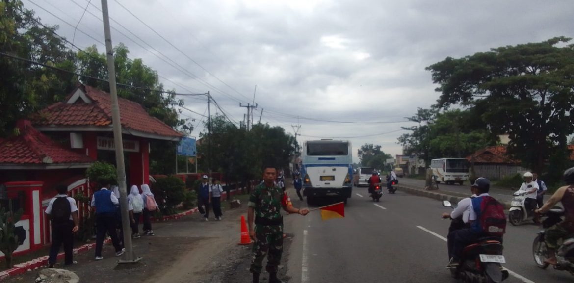 Anggota Koramil 1605 Sukagumiwang Indramayu Bantu Menyeberangkan anak sekolah