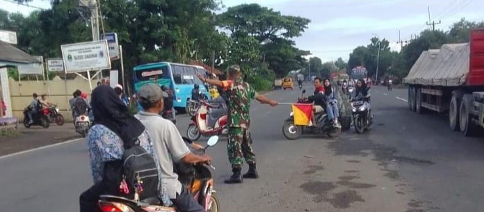 Anggota Koramil 1605 Sukagumiwang Indramayu Bantu Menyeberangkan anak sekolah