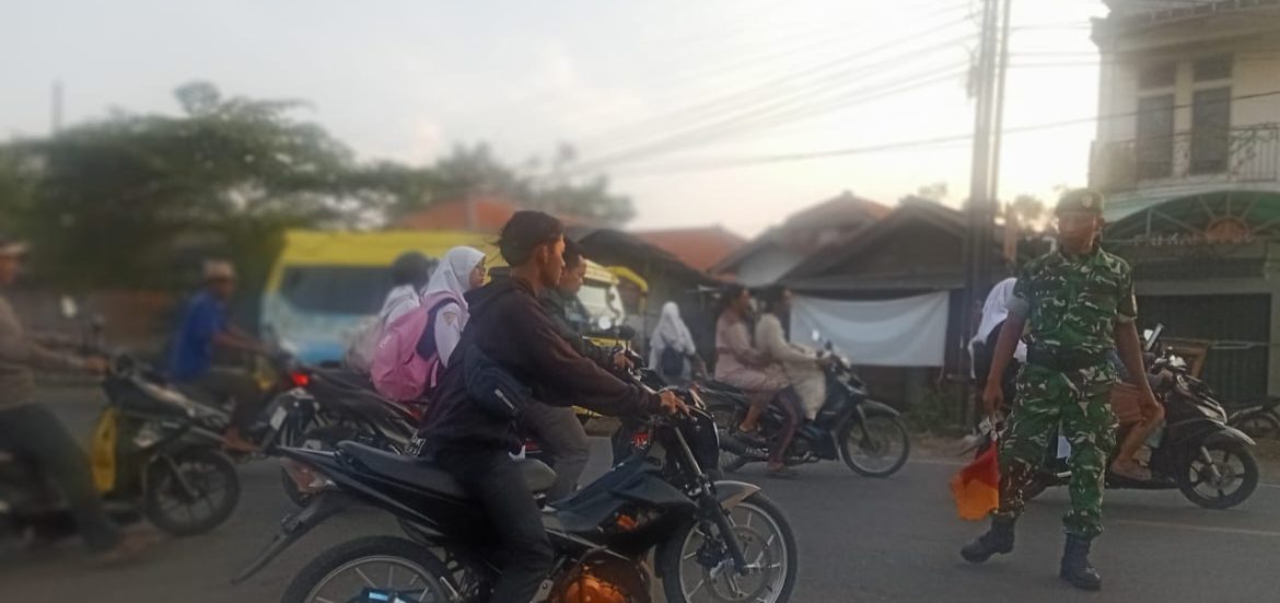 Babinsa Koramil 1609 Juntinyuat Bantu Masyarakat dan Anak-Anak Sekolah Menyebrang Jalan Raya Juntikebon