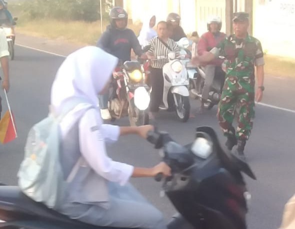 Babinsa Koramil 1605 Sukagumiwang Bantu Menyeberangkan Anak sekolah di Jalan Raya Candangpinggan