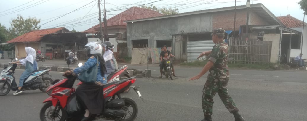 Babinsa Koramil 1605 Sukagumiwang Bantu Menyeberangkan Anak Sekolah