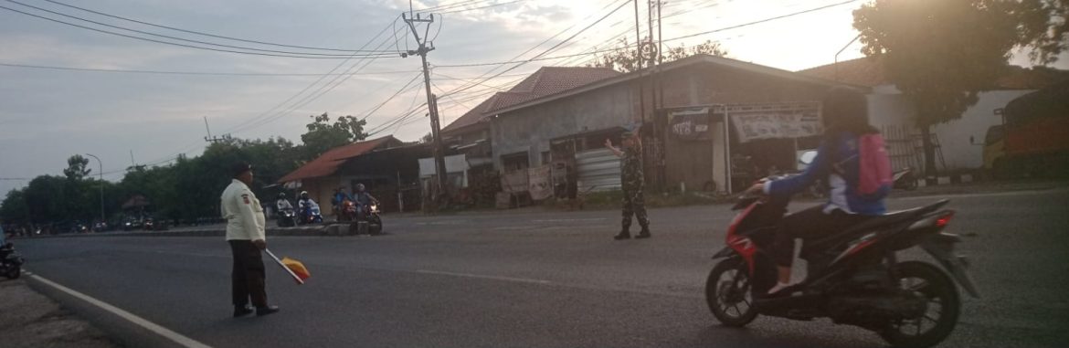 Anggota Koramil 1605 Sukagumiwang Bantu Menyeberangkan anak sekolah di Jalan Raya Candangpinggan