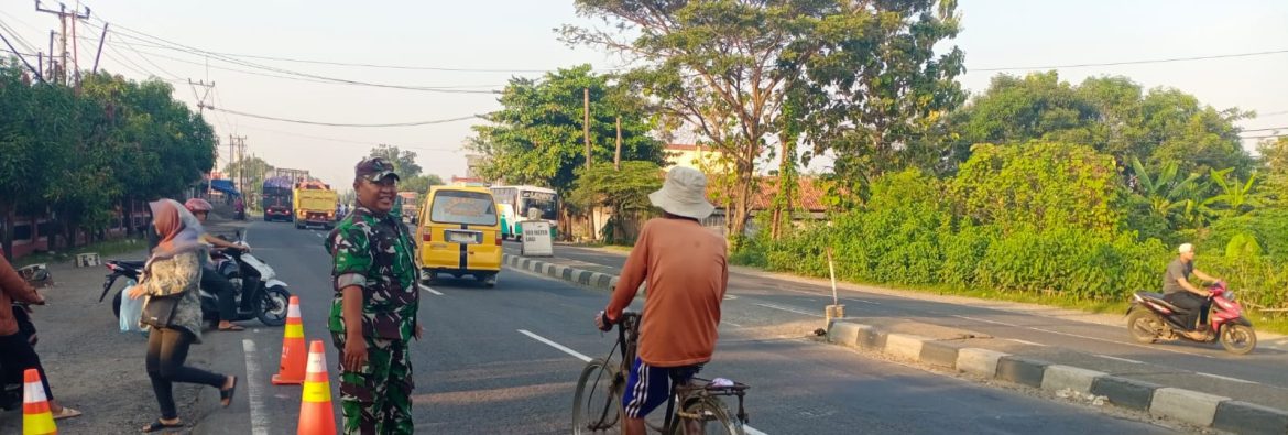 Babinsa Koramil 1605 Sukagumiwang Bantu Seberangkan Anak Sekolah di Jalan Raya Cadangpinggan