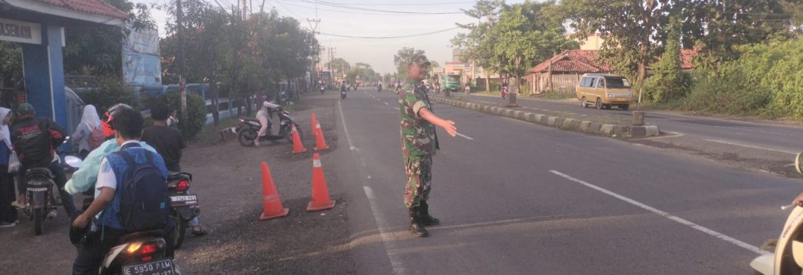 Babinsa Koramil 1605 Sukagumiwang Sigap Bantu Seberangkan Pelajar di Jalan Raya Cadangpinggan